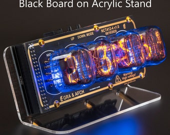 Może przedstawiać: Czarny i złoty zegar IN-12 Nixie Tubes z czarną tablicą i akrylowym stojakiem. Zegar wyświetla godzinę 10:30:20. Zegar ma etykietę ostrzegawczą z napisem "Ostrzeżenie! Wysokie napięcie!"