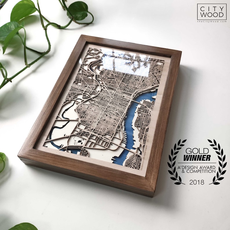 May include: A framed wooden map of Philadelphia, Pennsylvania, with a blue water feature. The frame is made of dark wood and has a gold "Gold Winner" award sticker with the text "A' Design Award & Competition 2018".