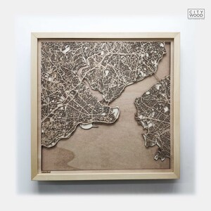 May include: A wooden map of Istanbul, laser cut and mounted in a light wood frame. The map shows the city's streets and waterways in detail.