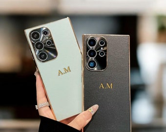May include: Two personalized phone cases, one light green and one black, with gold trim and the initials "A.M." in gold lettering.