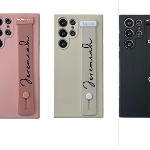 May include: Three phone cases with a personalised name "Jeremiah" printed on the strap. The cases are pink, beige, and black.