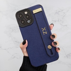 May include: A blue leather phone case with a black camera cutout and a gold strap with the word "stylish" and the letters "ZX" on it.