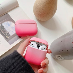 May include: Two pink gradient silicone cases for wireless earbuds. The cases are open and show the white earbuds inside.
