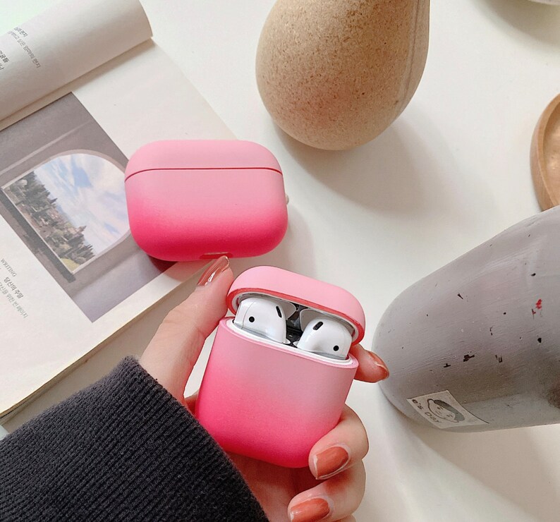 May include: Two pink gradient silicone cases for wireless earbuds. The cases are open and show the white earbuds inside.