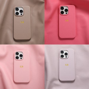May include: Four phone cases in different colors: brown, pink, light pink, and light purple. Each case has a camera lens cutout and the initials "S.B." printed in gold.