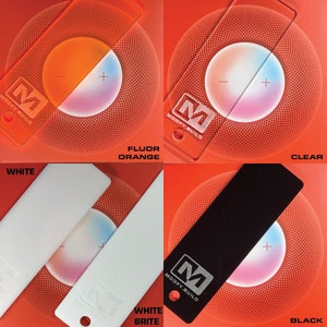 May include: Four different color swatches of vinyl wrap film. The swatches are labeled "White", "Fluor Orange", "White Brite", and "Clear". Each swatch is placed on top of a red, circular object with a white plus and minus sign in the center.