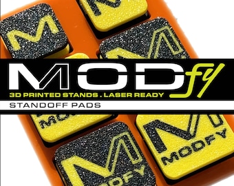 Könnte beinhalten: Ein Satz orangefarbener 3D-gedruckter Ständer mit schwarzen und gelben "M"-Buchstaben. Die Ständer sind mit "MODfy" und "STANDOFF PADS" beschriftet.