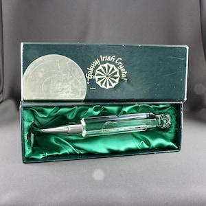 May include: A clear crystal pen in a green velvet lined box. The box is labeled "Galway Irish Crystal".