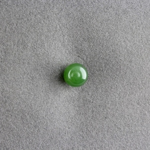 May include: A round, green jade bead with a circular pattern in the centre.