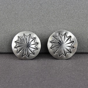 May include: A pair of silver earrings with a starburst design.