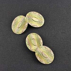 May include: Four gold-toned cufflinks with an oval design and intricate etched details. The cufflinks have a yellow and green color scheme.