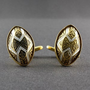 May include: A pair of gold cufflinks with a geometric design in black and white enamel.