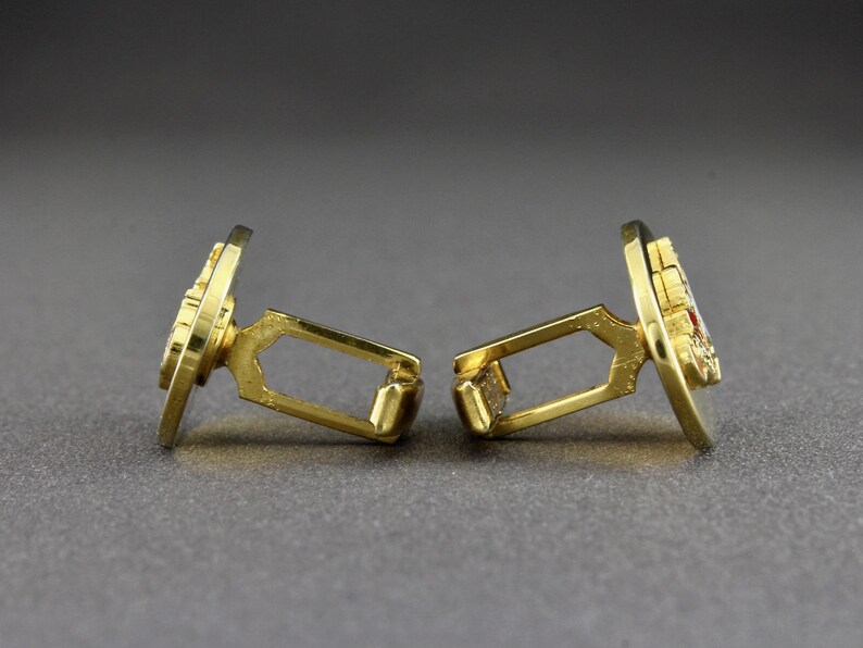 This is a side view of a pair of vintage cufflinks.
