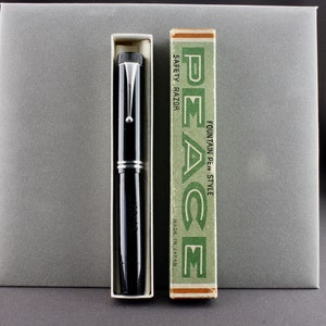 May include: A black fountain pen with silver accents in its original box. The box is green and white with the text "PEACE FOUNTAIN PEN STYLE MADE IN JAPAN" printed on it.