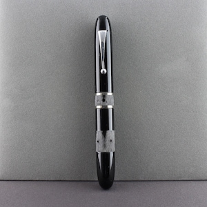 May include: A black fountain pen with silver accents and a black cap. The pen has a textured barrel and a silver clip.