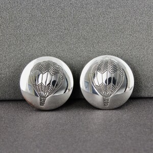 May include: A pair of silver earrings with a hot air balloon design. The balloons are detailed with a geometric pattern.