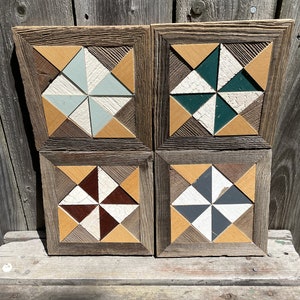 May include: Four wooden framed square wall art pieces with a geometric pattern of white, brown, tan, green, and gray triangles. The frames are made of reclaimed wood.