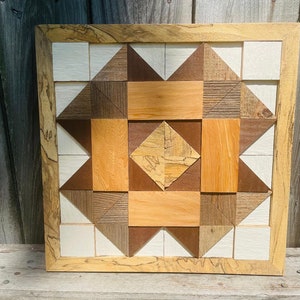 May include: A framed wooden wall art piece with a geometric pattern of squares and triangles in shades of brown, white, and beige.