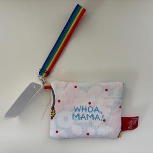 May include: A small, square, white floral print pouch with the text "WHOA, MAMA!" in blue. It has a rainbow wrist strap and a red tag that says "Becky Neff".