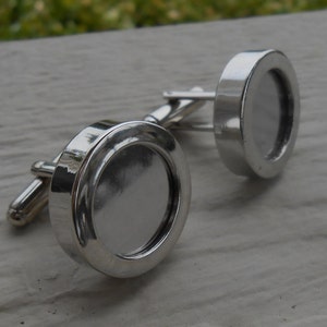 May include: A pair of silver cufflinks with round, clear glass inserts. The cufflinks are designed to hold a small photo or other memento.