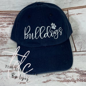 May include: A navy blue baseball cap with white embroidery that reads "Bulldogs" with a white paw print above the text.