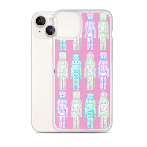 May include: A pink phone case with a pattern of blue, green, and white nutcracker soldiers. The case is clear and shows the phone's camera lens.