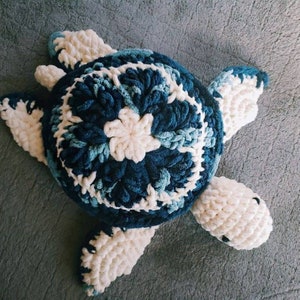 May include: A crocheted stuffed sea turtle toy with a blue and white shell and white limbs.