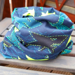 Könnte beinhalten: Ein blauer und grüner Nackentuch mit einem geometrischen Muster aus Haien und Sternen. Der Stoff ist weich und dehnbar.