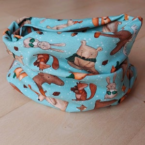Könnte beinhalten: Ein hellblauer Stoff-Halswärmer mit einem Waldtier-Druck. Der Druck zeigt Eichhörnchen, Kaninchen, Hirsche und Bären.