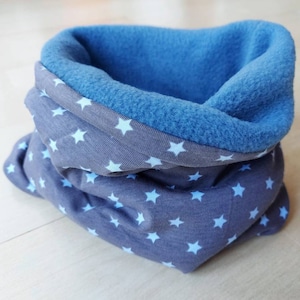 Könnte beinhalten: Ein grauer und blauer Halsschmeichler mit einem weißen Sternenmuster. Der Halsschmeichler ist aus weichem Fleece-Material gefertigt.