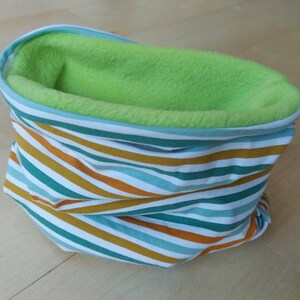 Könnte beinhalten: Ein gestreifter Halsschmeichler mit grünem Fleecefutter. Der Halsschmeichler ist aus einem weichen, dehnbaren Stoff gefertigt und perfekt, um sich im Winter warm zu halten.