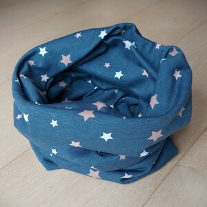 Könnte beinhalten: Ein türkisfarbener Halsschmeichler mit einem Muster aus weißen und rosafarbenen Sternen.