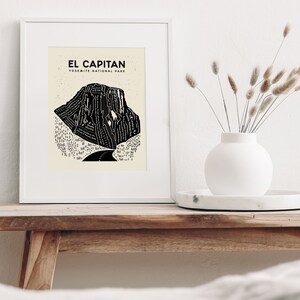 May include: A framed black and white illustration of El Capitan in Yosemite National Park. The illustration is a stylized depiction of the rock formation with a road winding through the base.