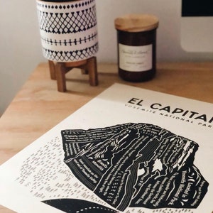 May include: Black and white illustration of El Capitan, a granite monolith in Yosemite National Park. The illustration shows the different routes and features of the rock face, including the Nose, a popular climbing route. The text "El Capitan, Yosemite National Park" is printed at the top of the illustration.