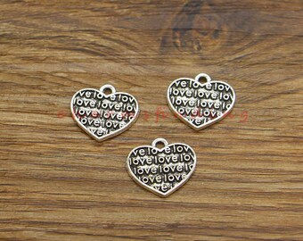May include: Three silver heart-shaped charms with the word "love" repeated on each charm.