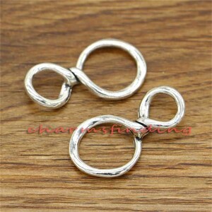 May include: Two silver-toned infinity symbol shaped metal connectors. The connectors have a smooth, slightly textured finish.