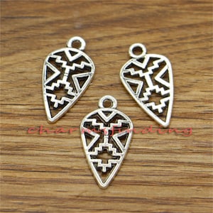 May include: Three silver-toned pendant charms with a geometric design. Each charm is shaped like a teardrop and features a repeating pattern of triangles and squares.