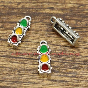 Pu&ograve; includere: Tre ciondoli d'argento a forma di semaforo. Ogni luce ha un colore diverso: verde, giallo e rosso. I ciondoli sono perfetti per aggiungere un tocco unico ai gioielli.