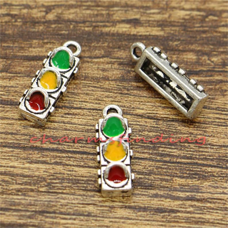 Pu&ograve; includere: Tre ciondoli d'argento a forma di semaforo. Ogni luce ha un colore diverso: verde, giallo e rosso. I ciondoli sono perfetti per aggiungere un tocco unico ai gioielli.