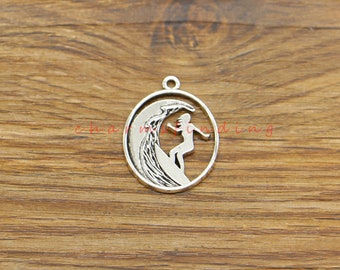 May include: Silver charm featuring a silhouette of a person surfing a wave. The charm is round and has a smooth, polished finish.