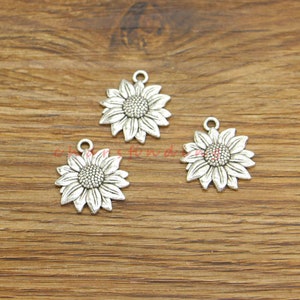 May include: Three silver-toned sunflower charms with a detailed design. The charms have a loop at the top for attaching to jewelry or other crafts.