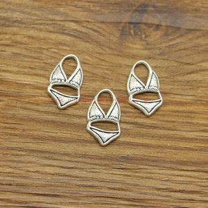 May include: Three silver-toned metal charms shaped like a bikini top. The charms have a textured surface and are detailed with small circles around the edges.