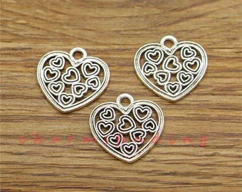 May include: Three silver-toned heart-shaped charms with a filigree design of smaller hearts. The charms have a loop at the top for attaching to jewelry.