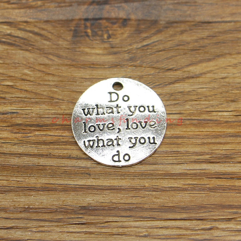 K&ouml;nnte beinhalten: Silberner Anh&auml;nger mit dem Text "Do what you love, love what you do".