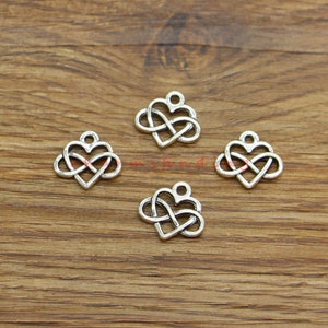 May include: Four silver-toned metal charms in the shape of an infinity symbol intertwined with a heart. The charms have a loop at the top for attaching to jewelry or other crafts.