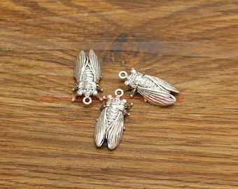 Könnte beinhalten: Drei silberne Zikaden-Anhänger mit detailliertem Design. Die Anhänger haben oben eine Öse zum Anbringen an Schmuck oder andere Bastelarbeiten.