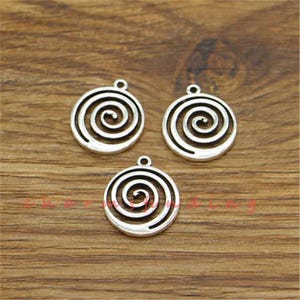 Può includere: Tre ciondoli in metallo color argento con un design a spirale. Ogni ciondolo ha un anello nella parte superiore per essere attaccato a una collana o un braccialetto.