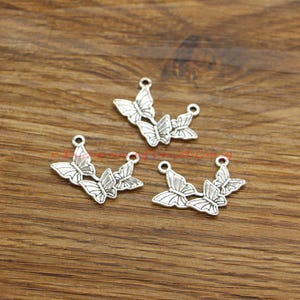 Puede incluir: Cuatro abalorios de mariposa plateados con un bucle en la parte superior para sujetarlos a joyas u otras manualidades.