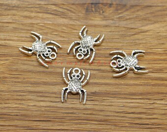 May include: Four silver-toned spider charms with a textured finish. The spiders have eight legs and two beady eyes. The charms are perfect for adding a spooky touch to jewelry or crafts.