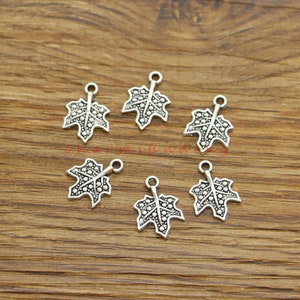 May include: Six silver-toned maple leaf charms with a textured surface. Each charm has a loop at the top for attaching to jewellery or other crafts.